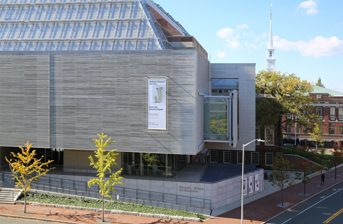 A view of the Harvard Art Museums modern gray wood exterior that floats over Prescott Street.